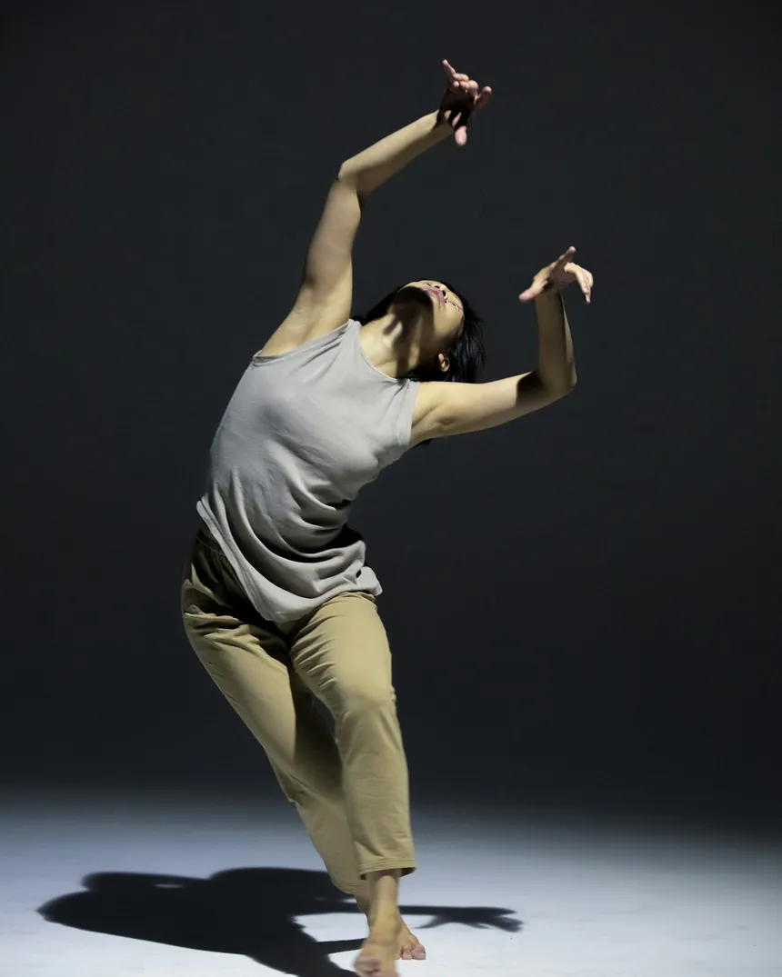 Silueta de una persona en pleno movimiento de danza sobre fondo oscuro